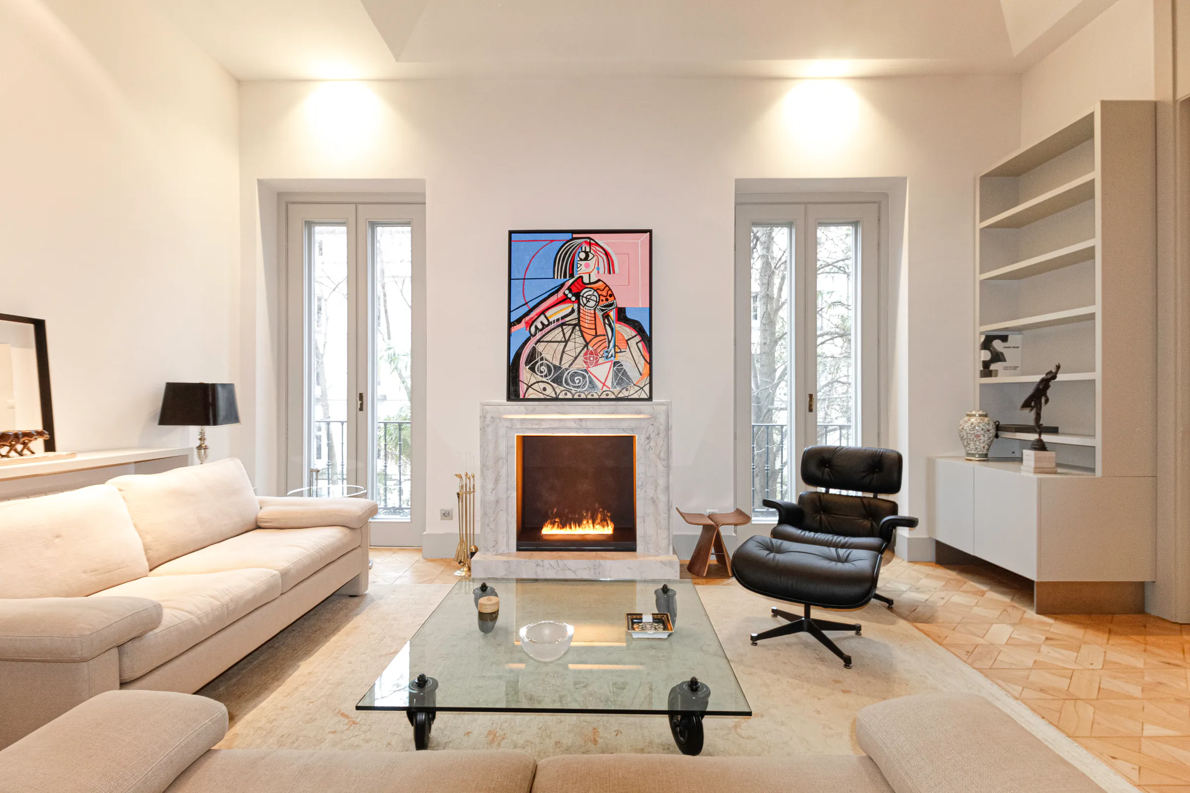 Salón de un piso en la calle Claudio Coello de Madrid, con chimenea de mármol, butaca Eames y parqué clásico