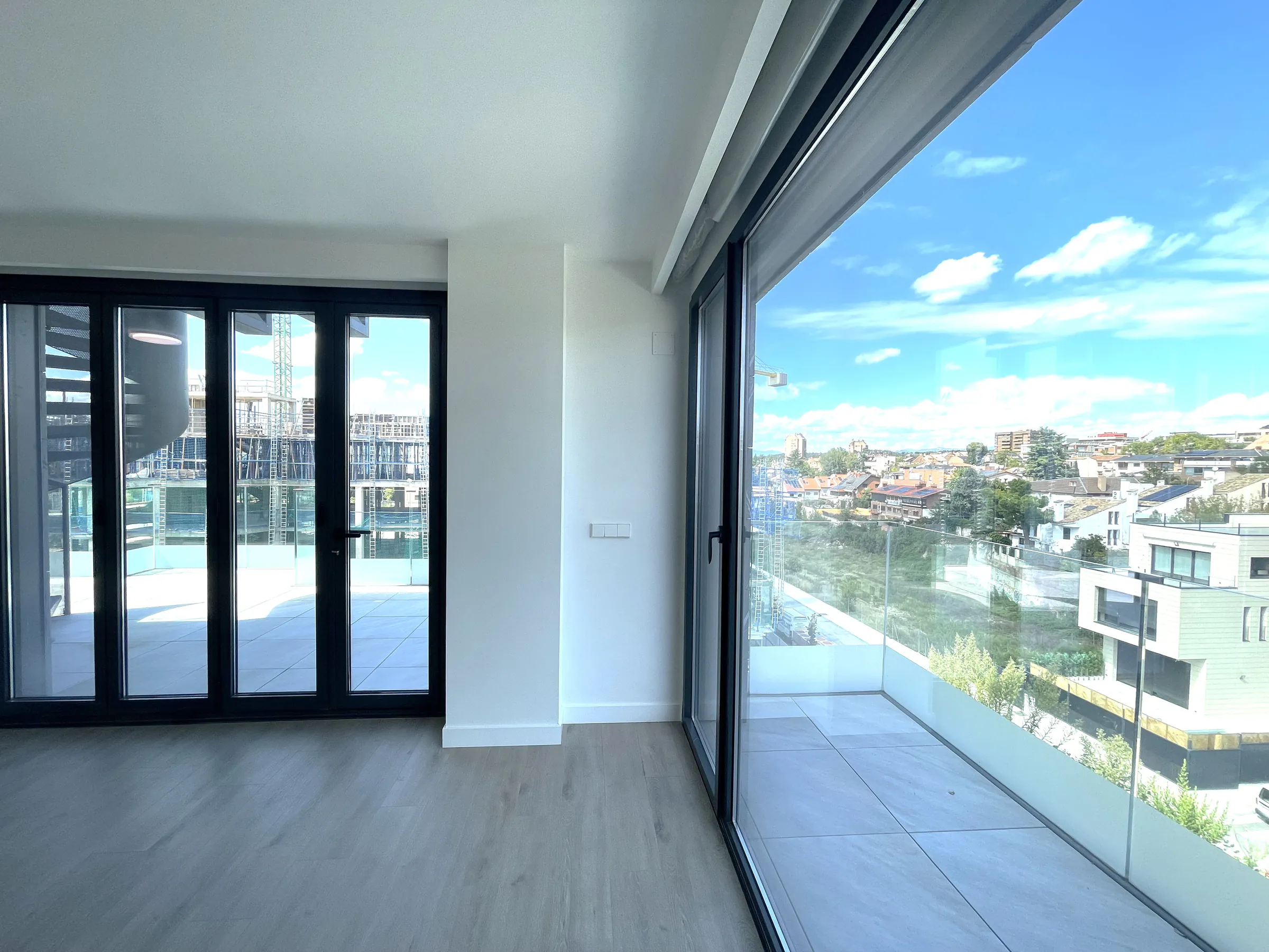 Salón de un ático en alquiler en Madrid, con carpintería negra y ventanal de esquina con vistas