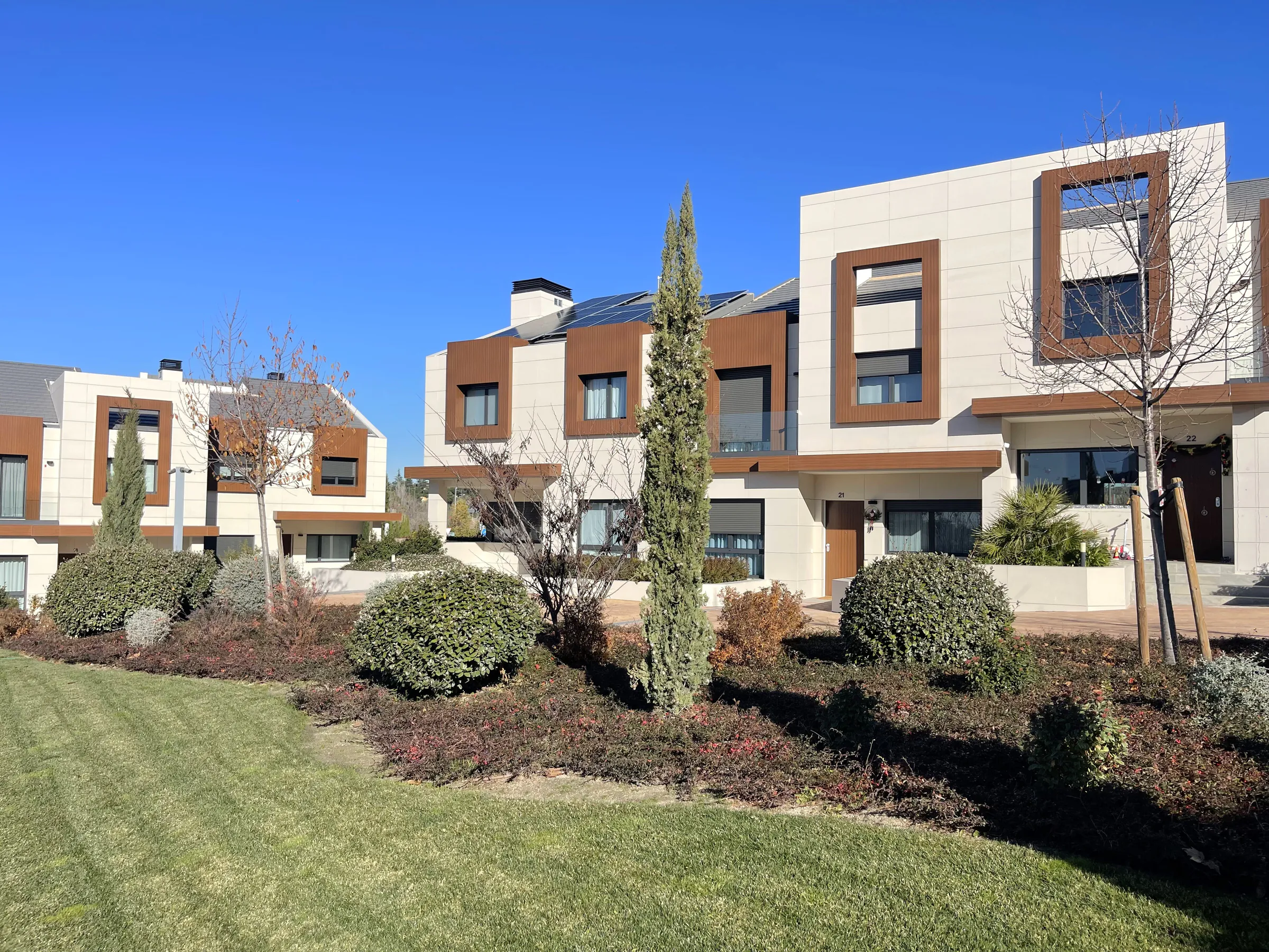 Chalets adosados de obra nueva con fachada blanca, jardín y ciprés